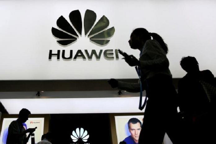 FILE PHOTO: People walk past a sign board of Huawei at CES Asia 2016 in Shanghai