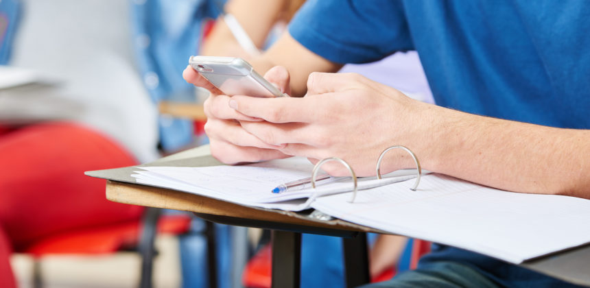Schüler liest SMS auf dem Smartphone