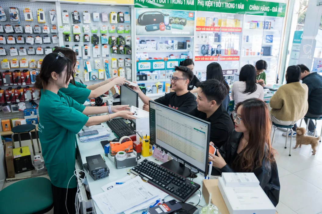 Nhân viên trao thiết bị cho khách tại quầy cửa hàng điện thoại