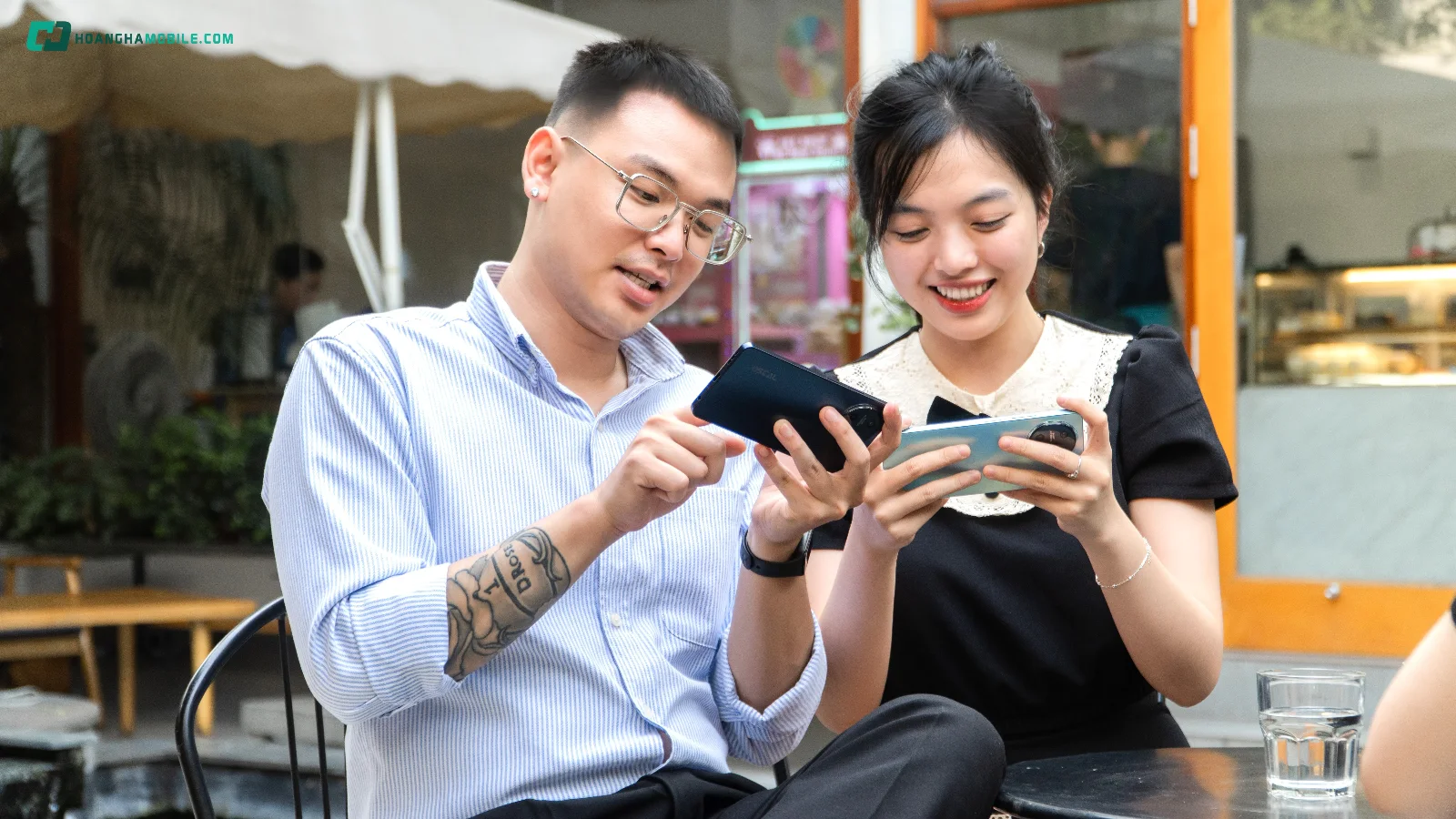 Hai người ngồi cạnh nhau sử dụng điện thoại